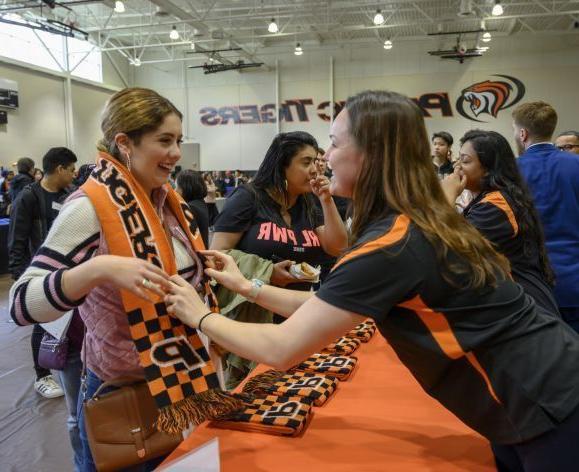 staff member giving student a Tiger scarf